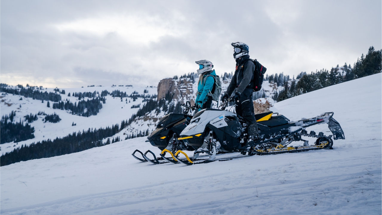 two Ski-Doo riders overlooking a mountain range