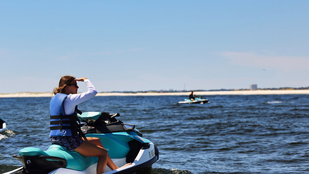 Une femme regardant au loin des dauphins sur un Sea-Doo