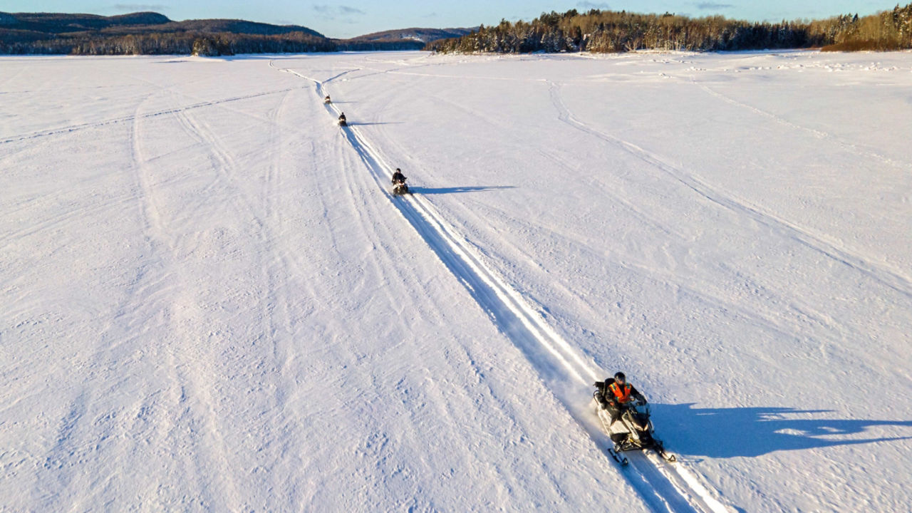 Un groupe de motoneigistes traversant un lac gelé