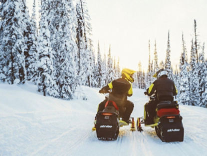 Deux motoneigistes discutant sur leur Ski-Doo dans un sentier.