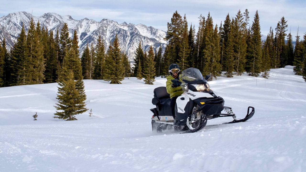 Un homme heureux conduisant un Ski-Doo sur de la neige fraîche.