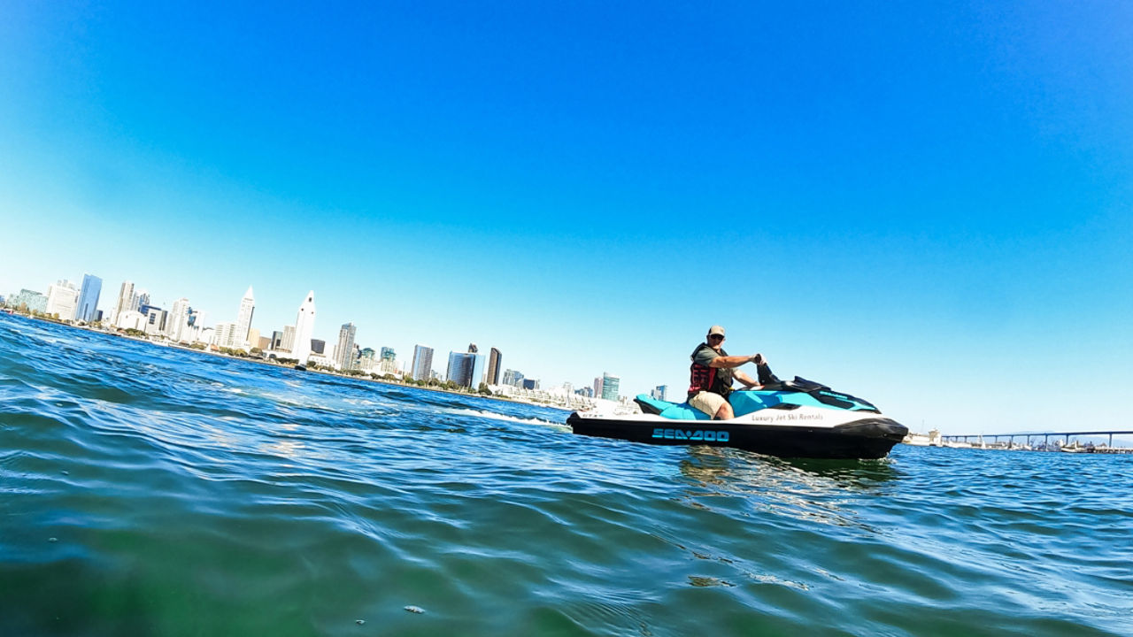 Un homme sur un Sea-Doo au milieu de l'eau avec une ville en arrière-plan