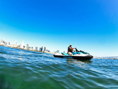 Un homme sur un Sea-Doo au milieu de l'eau avec une ville en arrière-plan