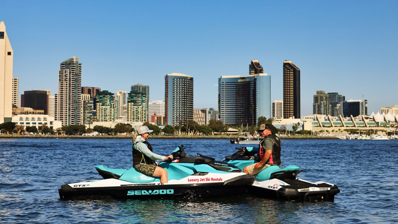 Un homme sur un Sea-Doo au milieu de l'eau avec une ville en arrière-plan