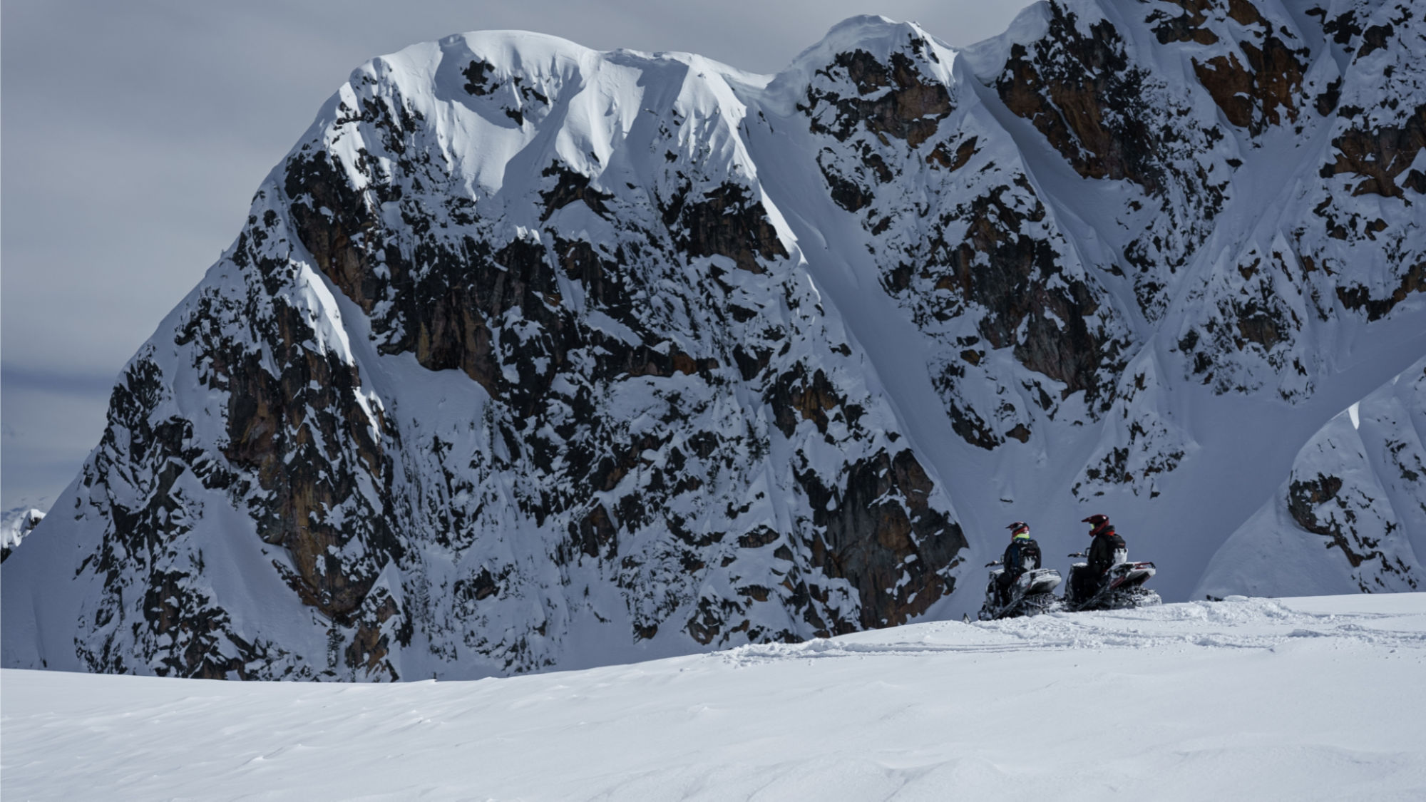 Two snowmobilers looking at the British Columbia peaks