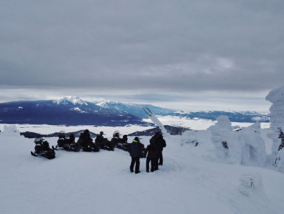 Motoneigistes admirant la vue sur les montagnes