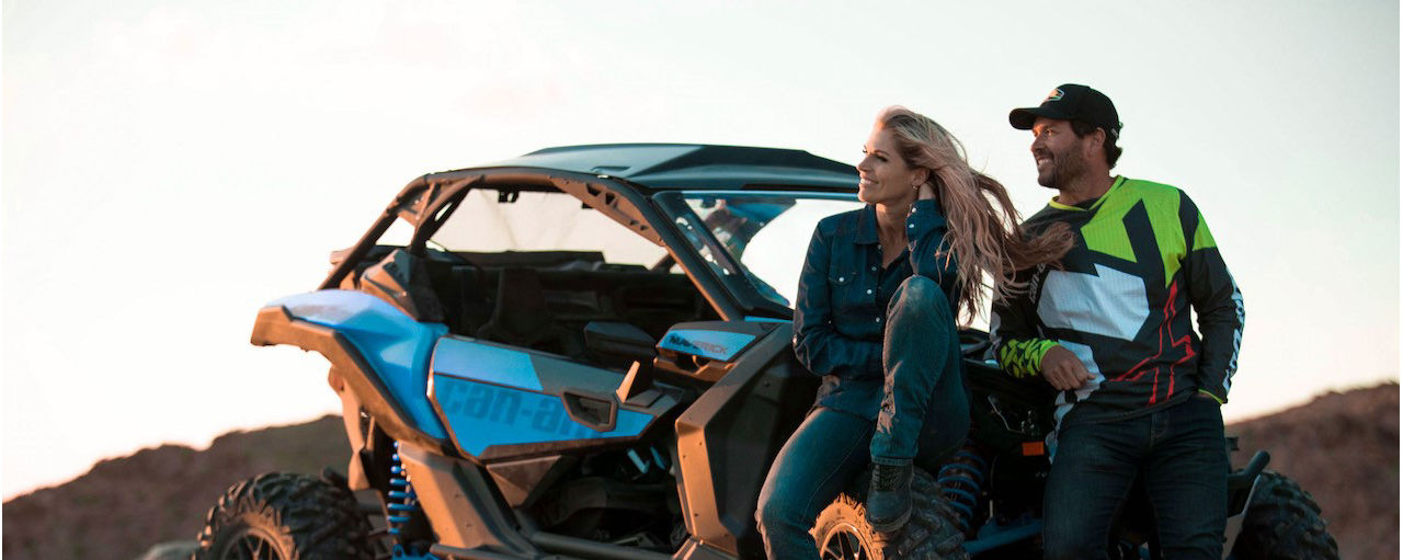 Un couple se reposant à côté d'un véhicule Can-Am Off-Road