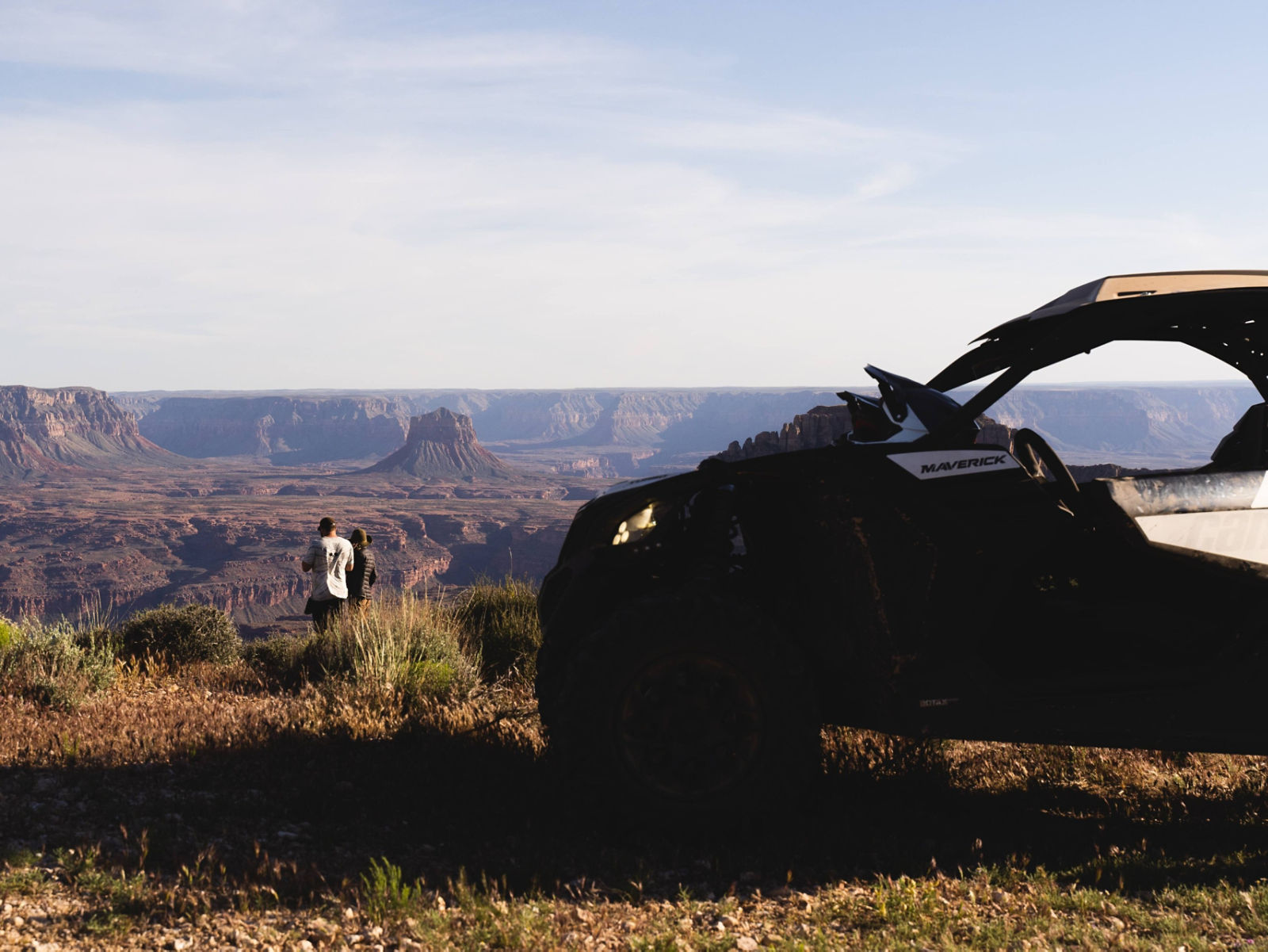 Two people watch over a cliff with a Maverick in the front