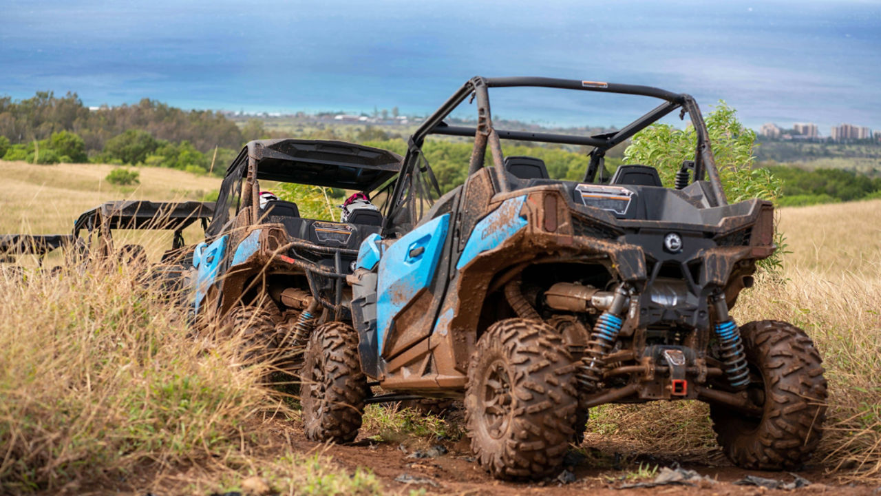 A rider waving inside a muddy vehicle