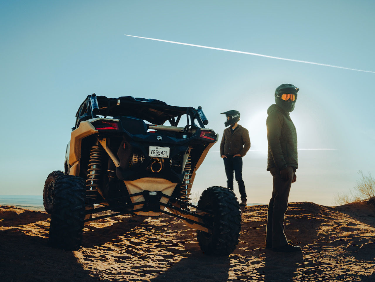 Two persons in the mountain next to a Can-Am SSV