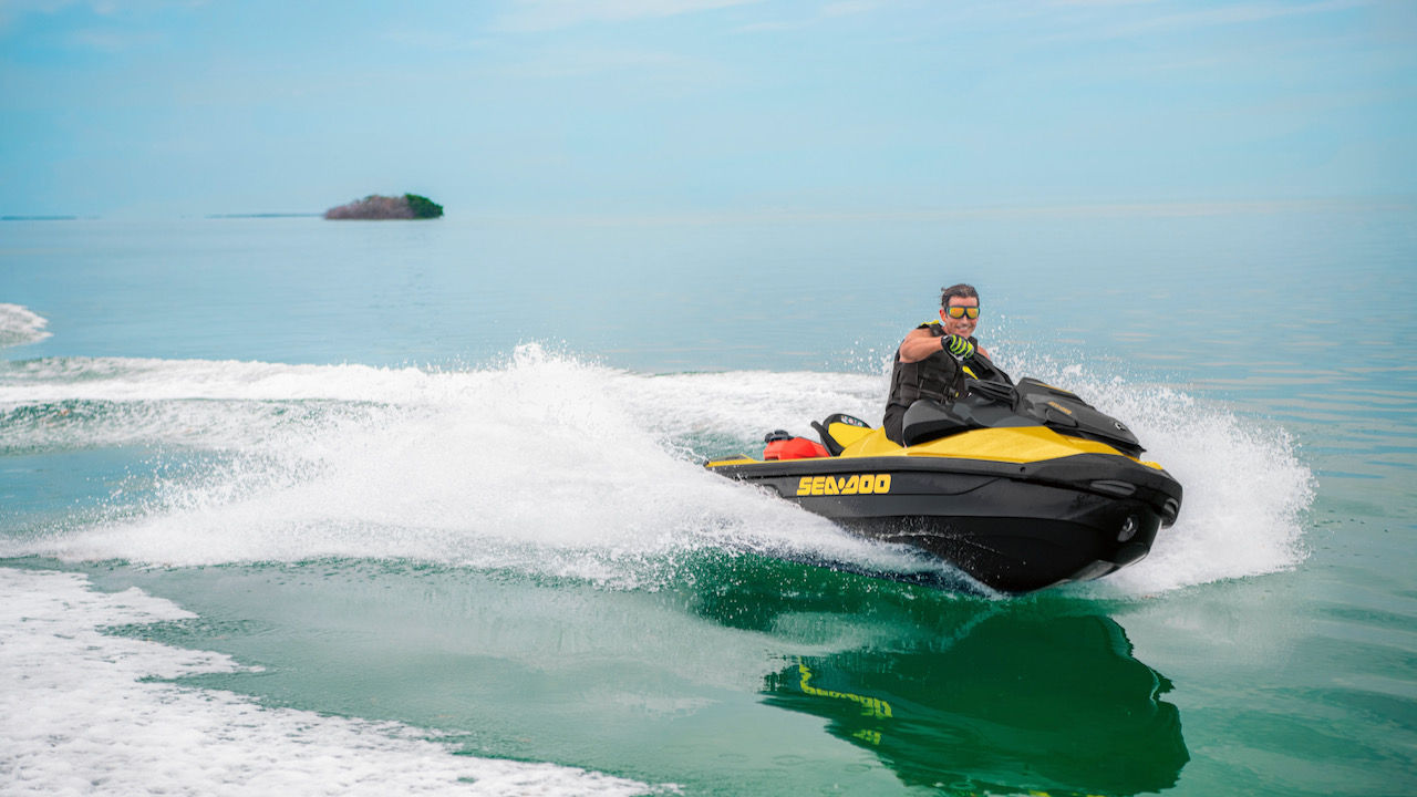 Un homme tournant avec une motomarine Sea-Doo avec une île en arrière-plan