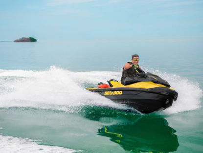 Un homme tournant avec une motomarine Sea-Doo avec une île en arrière-plan