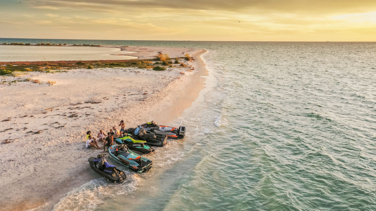 Amis sur une plage avec des motomarines garées