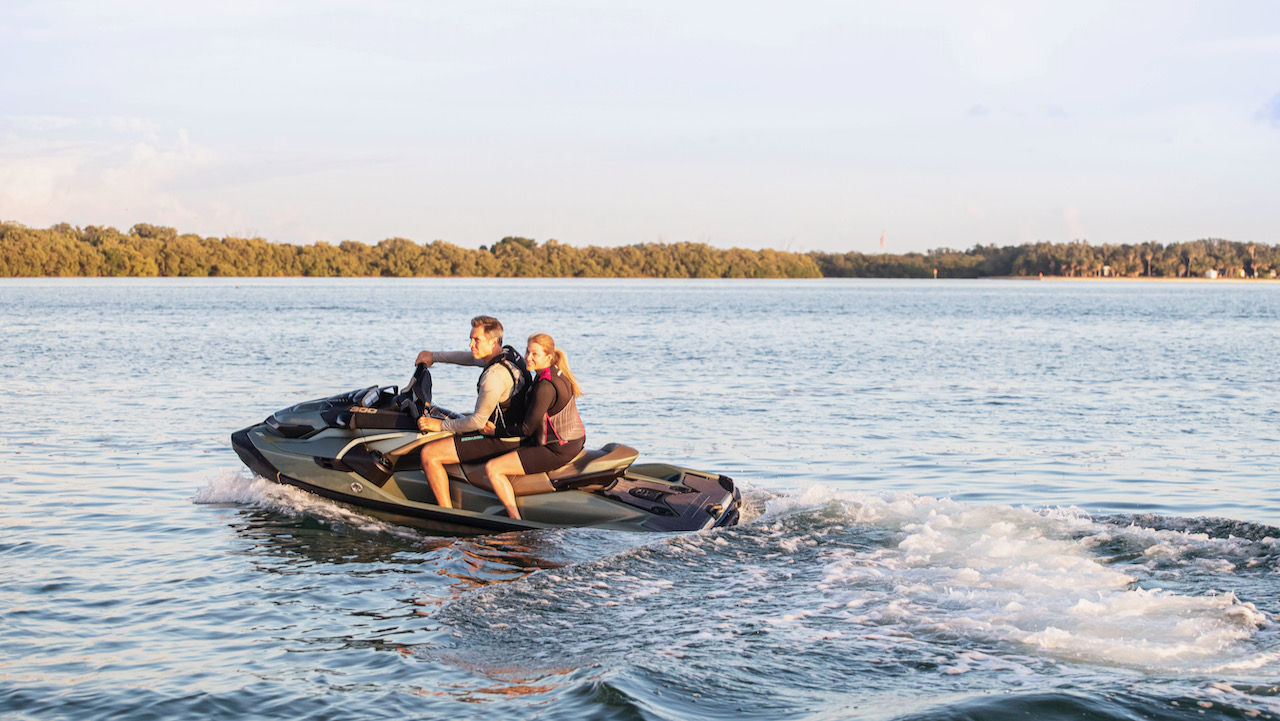 A couple going off a personal watercraft parked on a beach