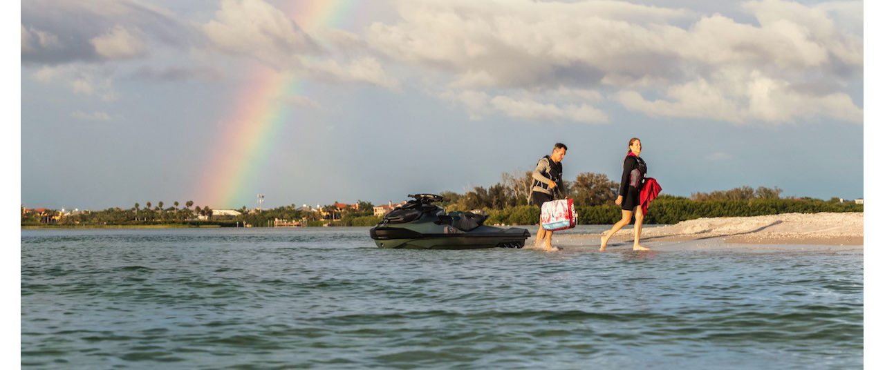 A couple going off a personal watercraft parked on a beach