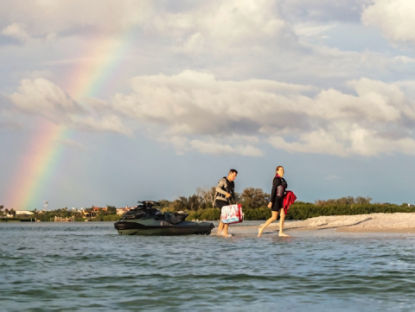 A couple going off a personal watercraft parked on a beach