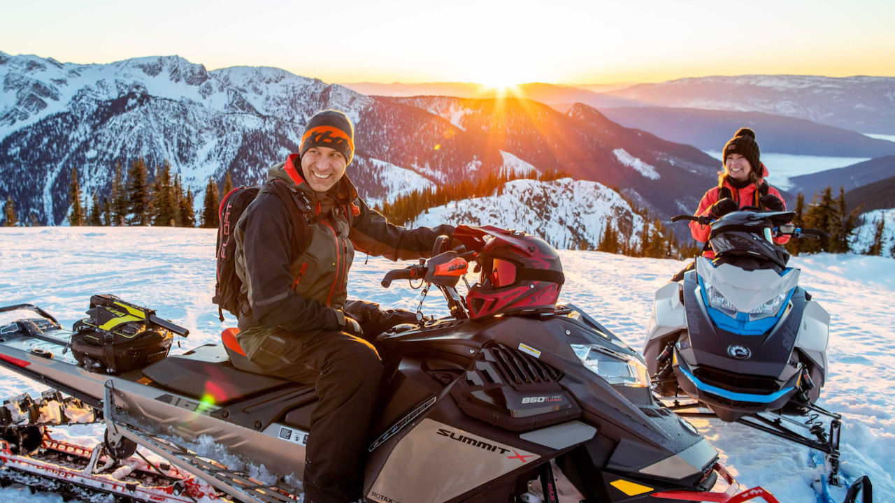 couple faisant le signe de la main sur un Ski-Doo