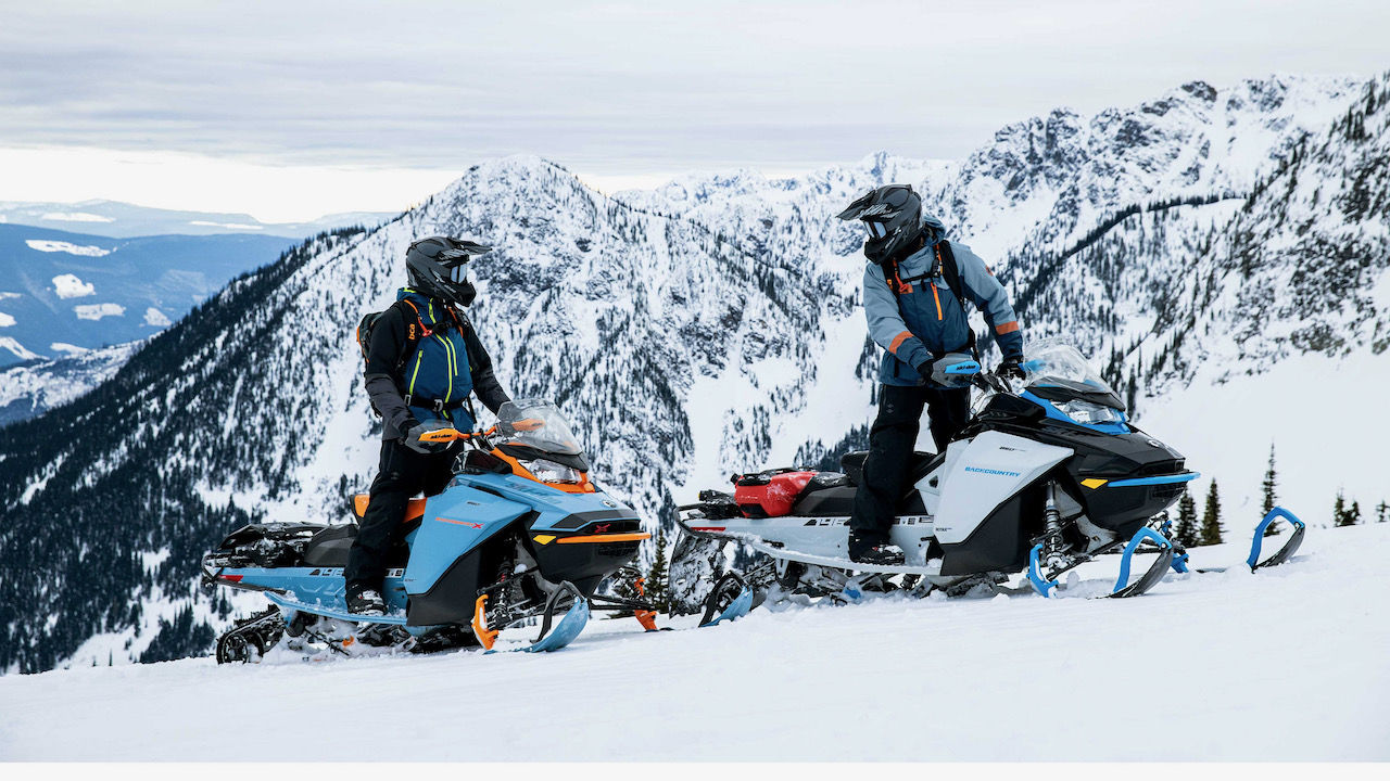 deux pilotes de ski-doo dans les montagnes